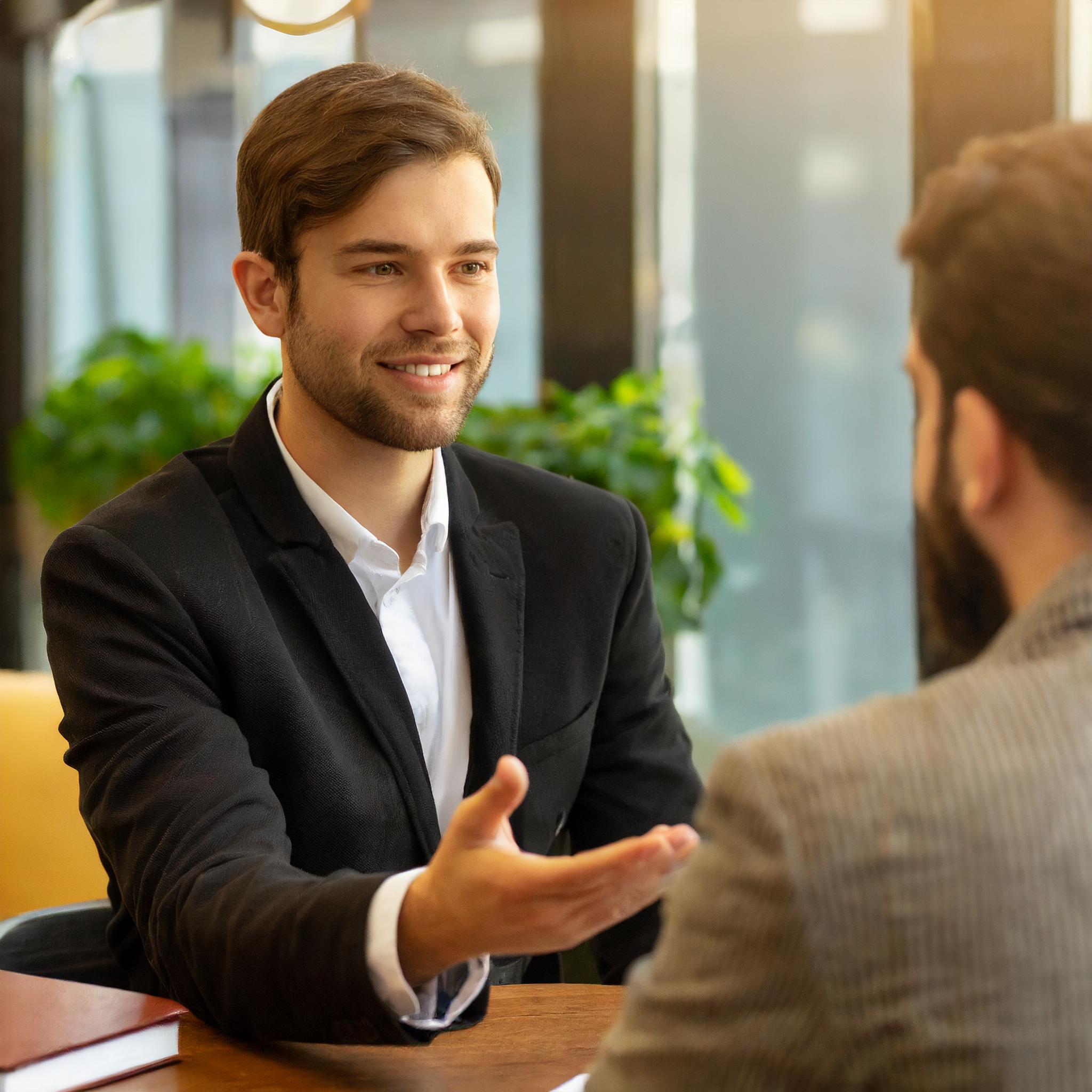 Freundlicher Steuerberater im Gespräch mit einem Kunden in einem modernen Büro.
